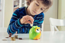 Enfant mettant des pices dans une tirelire 