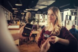 Jeune femme rglant un achat par carte bancaire