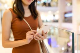 Femme utilisant un smartphone dans une galerie marchande