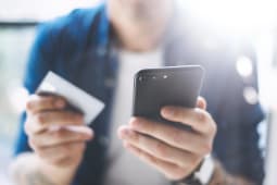Jeune homme tenant un iPhone et une carte bancaire