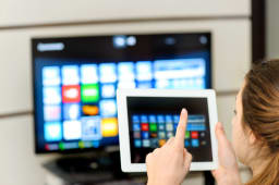 Une femme consultant sa tablette devant la tlvision