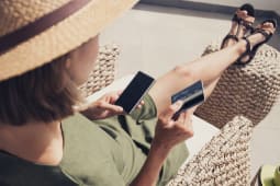 Jeune femme en vacances utilisant sa carte bancaire et son mobile
