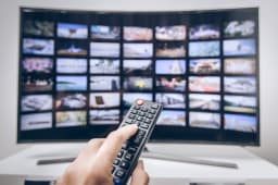 Une main presse les boutons de la tlcommande d'une smart TV