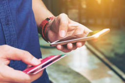 Un homme tient un mobile et une carte bancaire