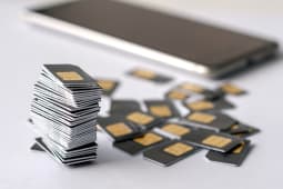 Pile de cartes SIM avec smartphone en arrire-plan