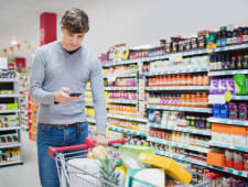 Homme consultant son smartphone en faisant ses courses