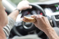 Un conducteur mange un sandwich au volant