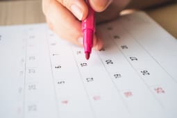 Main avec stylo crivant sur un calendrier 