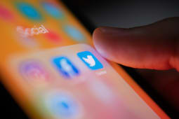 Un usager d'iphone touche le logo Twitter sur son cran
