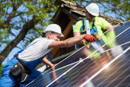 hommes installant des panneaux solaires sur un toit