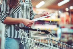 Femme devant un caddie lisant un ticket de caisse