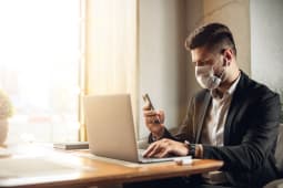 banquier devant son ordinateur portant un masque