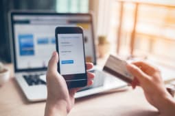 Homme utilisant sa banque en ligne sur smartphone et ordinateur 
