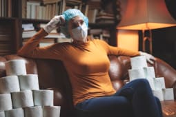 Femme masque et rouleaux de papier toilette