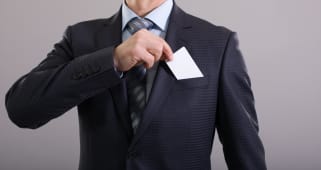 Un homme en costume range sa carte bancaire dans sa poche