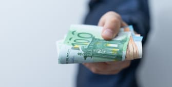 Un homme tient une liasse de billets en euros
