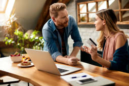 Couple discutant devant un ordinateur, carte bancaire  la main