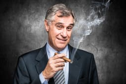 Un homme d'affaire souriant fume un cigare
