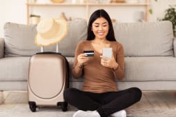 Une femme prpare son voyage une carte bancaire et un mobile  la main