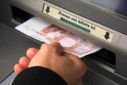 Une main retire des billets d'un DAB
