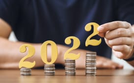 Homme posant les chiffres 2022 sur des piles de pices de monnaie
