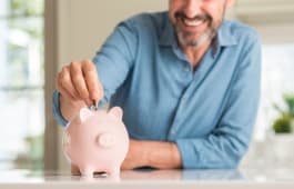 Un homme souriant met de l'argent dans une tirelire