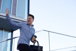 Un homme souriant fait un signe de main