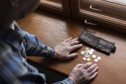 Un vieil homme cote les pices de son porte-monnaie