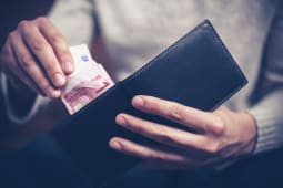 Un homme tirant un billet de 10 euros d'un portefeuille