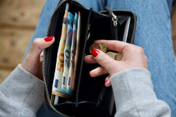 Une jeune femme compte son argent dans son porte-monnaie
