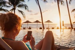 Une femme utilise son smartphone sur une plage
