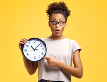 Une femme tient une horloge.
