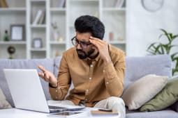 Un jeune devant son ordinateur l'air inquiet.
