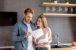 Un homme et une femme regardent un document l'air heureux.