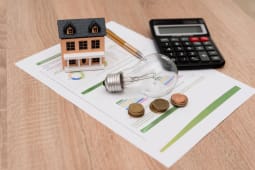 Une maison miniature, une ampoule et une facture.