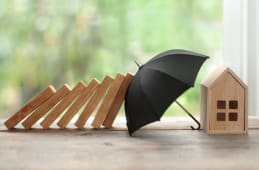 Une maison miniature protge par un parapluie.