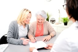 Une femme ge signe un document  ct d'une autre femme plus jeune.