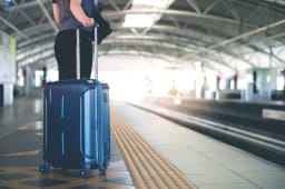 Quelqu'un tient une valise dans une gare.
