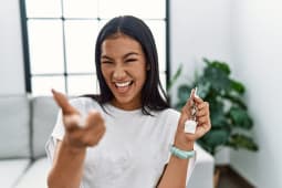 Une femme tient un porte clef en forme de maison dans sa main.