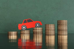 Une voiture miniature qui grimpe sur des piles de pices de monnaie.