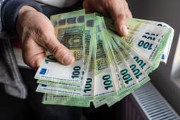 Quelqu'un tient plusieurs billets de 100 euros.