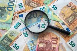 Des billets de banque en euros et une loupe.