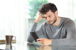 Un homme l'air inquiet regarde son tlphone.