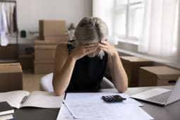 Une femme regarde un document et se prend la tte dans les mains.
