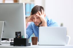 Un homme l'air inquiet devant son ordinateur.