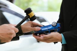 Un marteau symbole de la justice et une voiture miniature retourne.