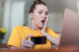 Une femme regarde une carte bancaire l'air effray.