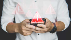 Quelqu'un regarde son tlphone affichant un symbole attention.