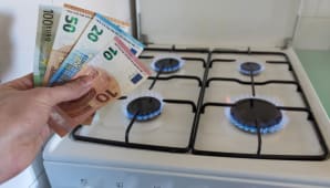 Quelqu'un tient des billets  ct d'une gazinire.