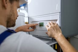 Un homme programme une chaudire gaz.